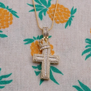 Vue détaillée du pendentif croix dorée avec couronne et pierres de zircone scintillantes