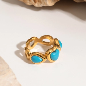 Detailed view of a gold heart and drop-shaped ring with blue stones on a stone base