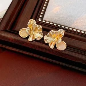 Vintage flower earrings in gold finish with cat-eye opal bead on a rustic wood background