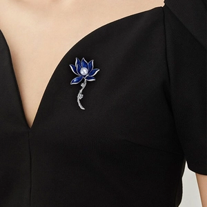 Elegant blue lotus brooch with pearl center worn on black V-neck top as a stylish accessory