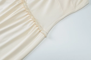 Close-up of beige summer dress waist with ruffle trim and ruched knot detail