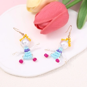 Detail of handmade beaded doll earrings featuring pearl heads on white ceramic tray