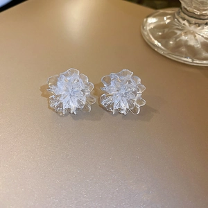Elegant clear resin flower stud earrings with silver pins on a warm champagne background