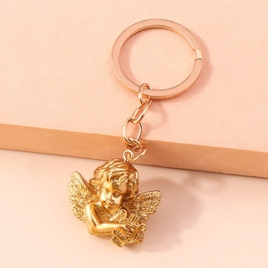 Detailed macro view of a golden angel pendant keychain with harp on a pink texture
