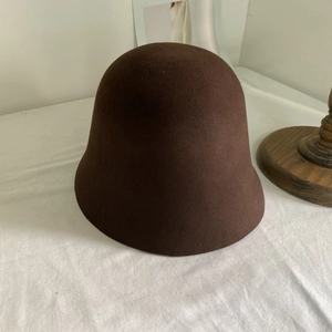 Texture détaillée en feutre de laine marron foncé sur un chapeau cloche minimaliste