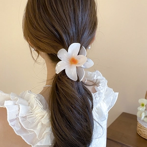 Détail d'une pince à cheveux lys blanc élégante au fini perlé portée en demi-queue