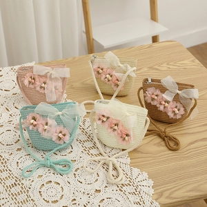 Vue à plat de sacs en paille colorés pour enfants avec fleurs et nœuds en dentelle sur bois