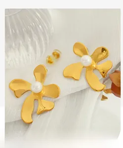 Détail de boucles d'oreilles fleur dorées avec perles blanches et design pétale élégant