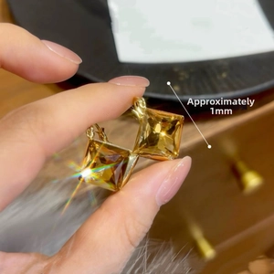 Détail macro de boucles d'oreilles en cristal ambré avec cadre doré, taille env. 1,6cm