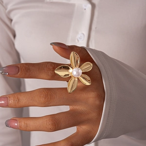Detailed view of elegant gold flower ring with pearl center worn on a model hand