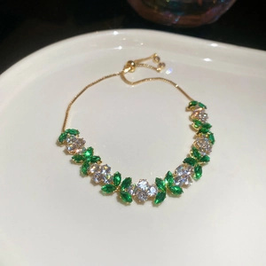 Detail of adjustable flower bracelet with green marquise zircon and golden chain
