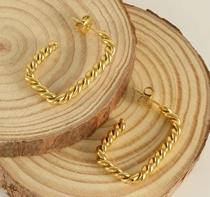Close-up of 18K gold-plated twisted U-shape hoop earrings on organic wood base