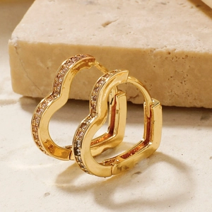 Elegant gold heart-shaped hoop earrings with clear cubic zirconia on stone background