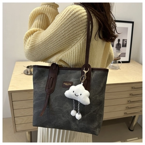Close-up of a charcoal grey canvas tote bag with brown leather straps and cloud charm