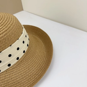 Close-up of a brown woven straw hat with a stylish polka dot ribbon detail