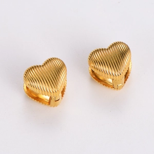 Detailed close-up of golden heart-shaped earrings with unique vertical striped relief design