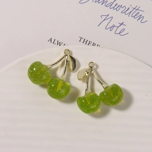 Close-up of translucent green cherry pendants with golden leaves on a white ceramic plate