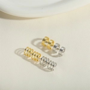 Gold and silver grid pattern and multilayer ear cuffs on a minimalist ceramic tray