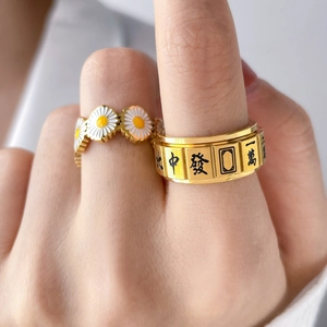 Detail of spinning mahjong ring and white daisy floral band on woman's hand