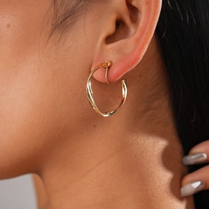 Detail of twisted gold metal hoop earring shown on ear for a minimalist jewelry style