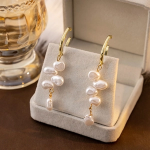 French vintage baroque pearl dangle earrings with gold hooks on a jewelry stand