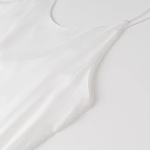 Dettaglio dell'abito sottoveste in raso bianco con trama in seta ed elegante scollatura