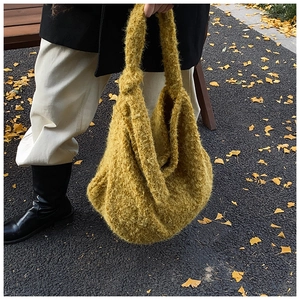 Close-up of yellow fuzzy wool tote bag texture against autumn ginkgo leaves background