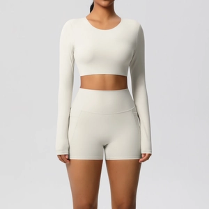 Detail van een crèmekleurige crop top met lange mouwen en hoge taille short met zak