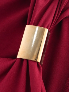 Detailed close-up of a golden rectangular metal buckle on burgundy pleated knit fabric