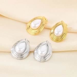Detail of drop-shaped pearl earrings in gold and silver finish on beige silk background
