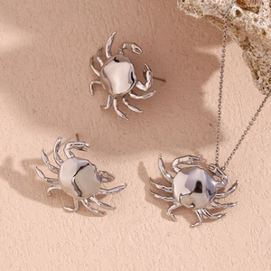 Polished silver crab jewelry set with necklace and stud earrings on ocean sand background