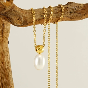 Minimalist stainless steel pearl necklace with gold bead on creative wood display