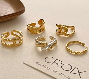 Close-up of five minimalist irregular gold and silver 925 silver rings on a display card