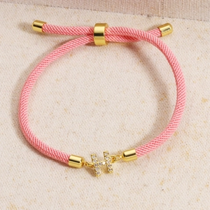 Macro detail of pink woven bracelet featuring a gold H pendant with micro-inlaid cubic zirconia