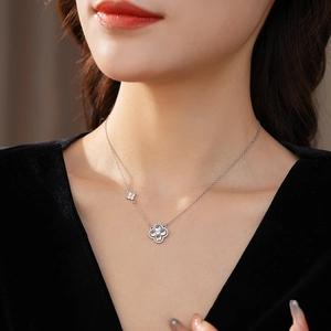 Collier trèfle argenté avec pendentif en zircone porté sur le cou d'un modèle