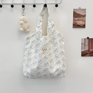 Gros plan du sac fourre-tout blanc avec motifs floraux bleus et écusson d'ours