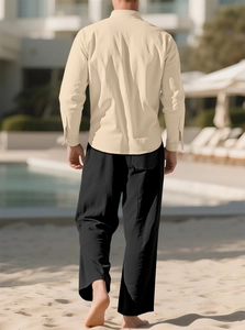 Men's apricot linen long sleeve shirt and black trousers set in beach resort setting