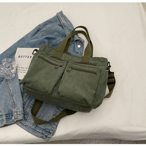 Green corduroy tote bag with double zippers and adjustable strap in a lifestyle setting