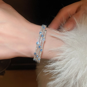 Macro shot of silver-tone three-layer bracelet with blue crystals and clear zircons