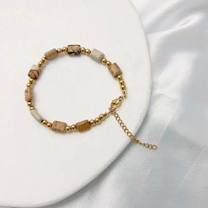 Detail of bohemian gold beads and natural stone cylinder beads bracelet with lobster clasp