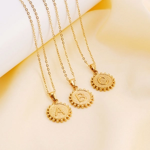 18K gold-plated stainless steel initial pendant necklaces on soft silk background