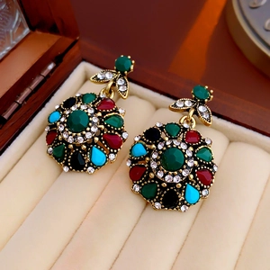 Detailed top view of vintage floral earrings with colorful crystals in a jewelry box