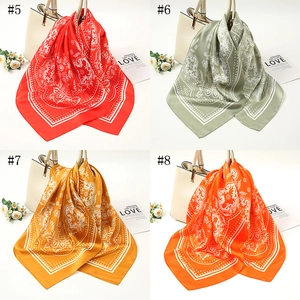 Detail of four colorful paisley silk scarves tied on bags in red, green, yellow, and orange
