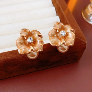 Détail de boucles d'oreilles fleur dorée avec cristal et perle dans un écrin en velours