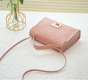 Close-up of pink woven texture small square bag with elegant golden metal square lock