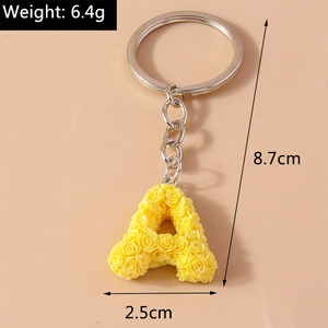 Detail view of a yellow resin letter A keychain with rose flower texture and metal ring