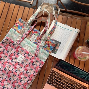 Detailed top view of vintage floral cotton tote bags with rose patterns on a wooden desk
