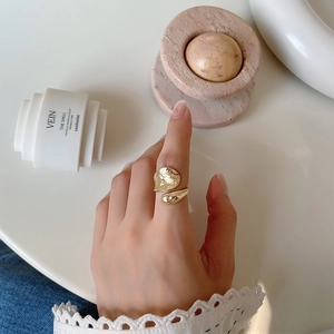 Detailed view of the gold open ring with irregular hammered texture on model finger