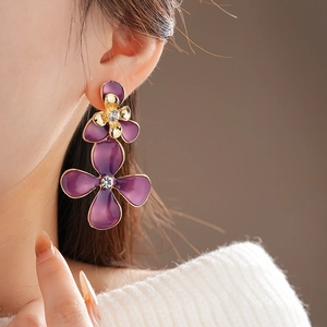 Detail of purple enamel flower earrings with gold edges and sparkling white rhinestones