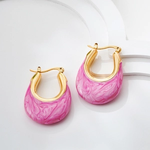 Macro detail of U-shaped gold earrings with pink marble enamel texture and glossy finish
